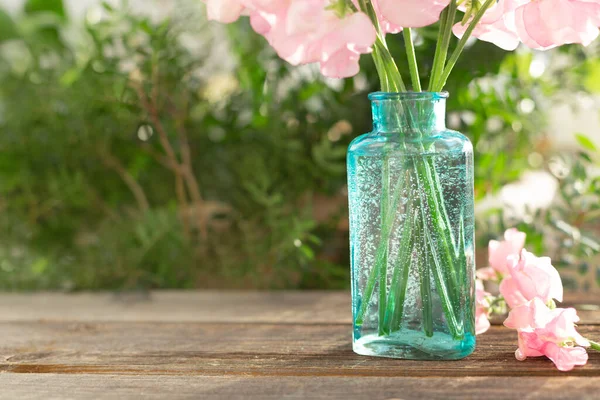 Bouquet of pink sweet peas Lathyrus in beautiful transparent vase on wooden background. Home garden,rustic. Spring concept. International Women\'s Day, March 8 and Valentine\'s Day,14 of February.