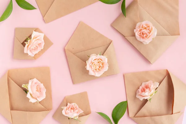 Paper open craft paper envelopes with full small rose flowers on color background. Trend spring, summer concept. Romance, love notes, greeting card for March 8 International Woman\'s, Valentine\'s day.