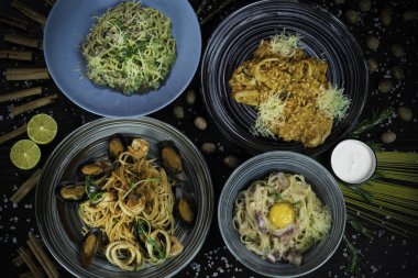 makarna, risotto, deniz ürünleri, domates, ceviz ve tarçınla süslenmiş koyu bir arka plan.