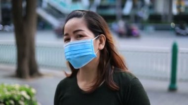 Yüzünde koruyucu tıbbi maske takmış Asyalı bir kadının portresi. Grip virüsü ve koronavirüs salgını her yerde..