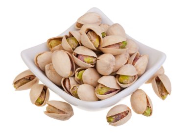 Beyaz zemin üzerinde kavrulmuş tuzlu şam fıstığı (kabuk olarak)