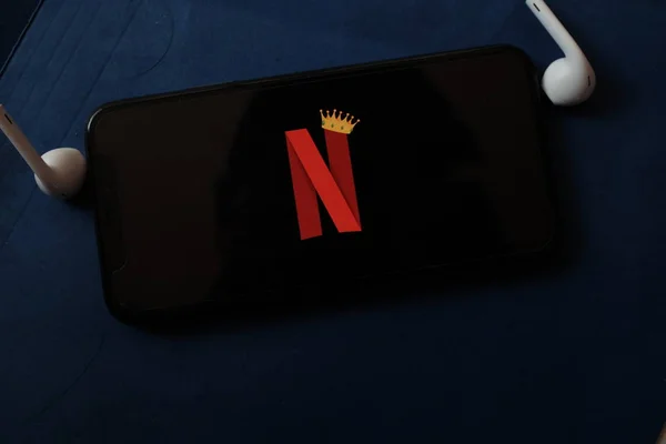 オンラインエンターテイメント企業である王冠を持つNetflixのロゴを持つスマートフォン ニューヨーク 2020年2月14日 — ストック写真