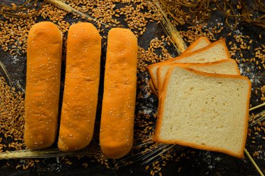 Hamburger breads, hot dogs, fully organic square breads, freshly prepared and baked on black background with wheat ears and wheat in bakery clipart