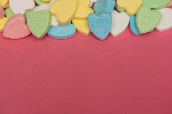 Doces coloridos em forma de coração no topo da superfície rosa, Valentim — Fotografia de Stock