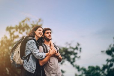Yazın yürüyüş yaparken gülümseyen ve eğlenen mutlu çift ve kadın turist portresi.
