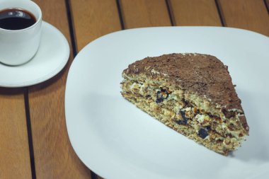 Bir fincan kahve ve bir parça kek Tahta masa kapları beyaz