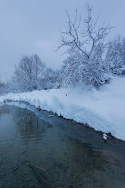Kış manzarası. Nehrin buzları üzerinde gün batımı. Ve ufuktaki şehir.