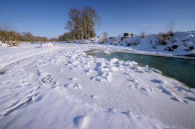 Güneşli bir günde kış nehri. Ağaçlardaki karlar karla kaplı..