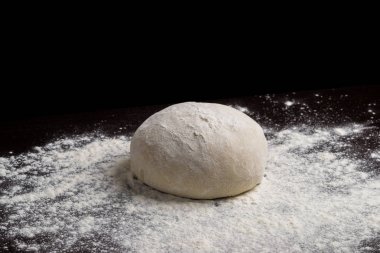 Raw pizza dough with flour on table