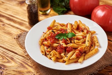 Soslu makarna ve beyaz tabakta fesleğen.