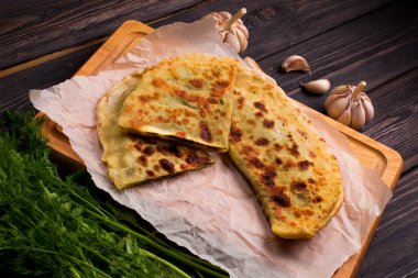 Ahşap masada otlar ve sarımsaklı fırında gözleme.