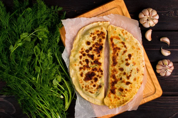 Baker 'ın geleneksel Ermeni yemeği (Zhengyalav şapkası, Zhangyalov şapkası) ince doğranmış otlar ve yeşil sebzelerle doldurulmuş bir tür düz ekmektir. Ev yapımı tarif. Üst görünüm ve yatay.