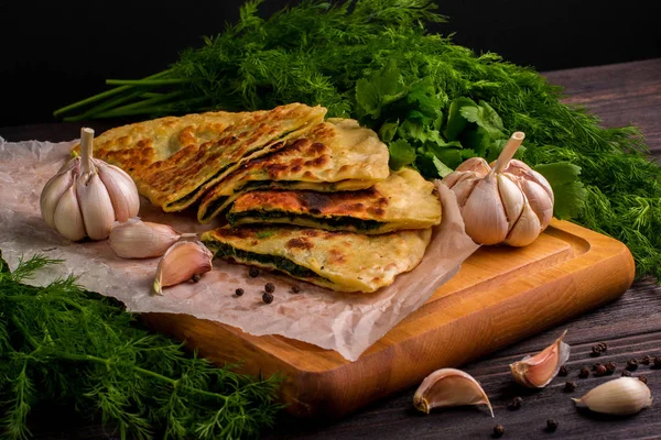 Baker 'ın geleneksel Ermeni yemeği (Zhengyalav şapkası, Zhangyalov şapkası) ince doğranmış otlar ve yeşil sebzelerle doldurulmuş bir tür düz ekmektir. Ev yapımı tarif. Üst görünüm ve yatay.