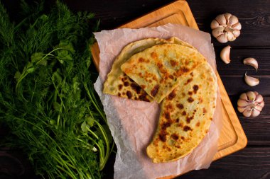 Ahşap masada otlar ve sarımsaklı fırında gözleme.