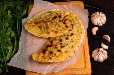 Baker 'ın geleneksel Ermeni yemeği (Zhengyalav şapkası, Zhangyalov şapkası) ince doğranmış otlar ve yeşil sebzelerle doldurulmuş bir tür düz ekmektir. Ev yapımı tarif. Üst görünüm ve yatay.