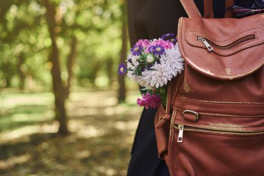 Sırt çantasında çiçekli bir kadın ormanda dikilirken