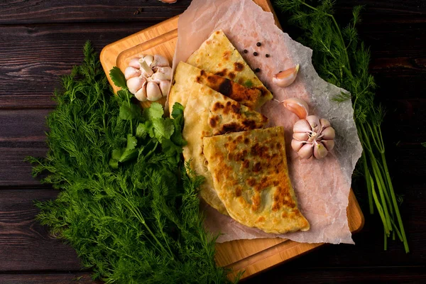 Baker 'ın geleneksel Ermeni yemeği (Zhengyalav şapkası, Zhangyalov şapkası) ince doğranmış otlar ve yeşil sebzelerle doldurulmuş bir tür düz ekmektir. Ev yapımı tarif. Üst görünüm ve yatay.
