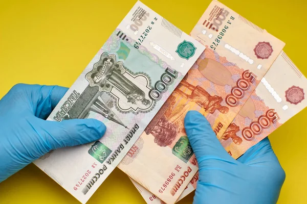 Eldivenli eller sarı arka planda para tutar..