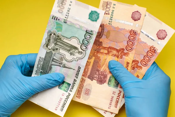 Eldivenli eller sarı arka planda para tutar..