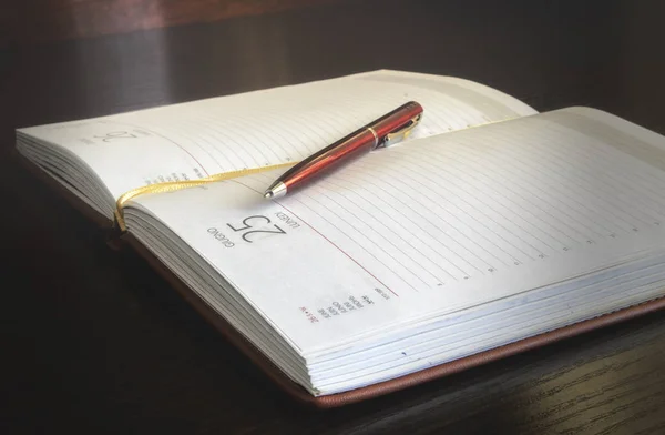 Open notebook and ball-point pen on a table.