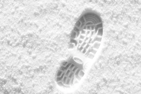 Track from a boot on white snow. Black and white photo.