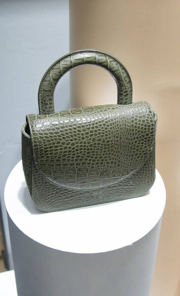 Женская сумка из кожи крокодила светло-зеленого цвета на полке в магазине
.