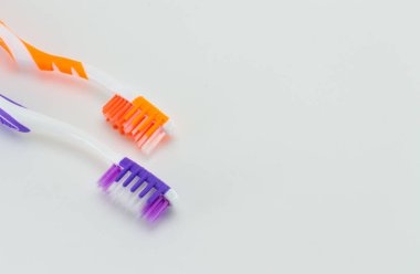 İki diş fırçası. Beyaz-turuncu ve beyaz-menekşe. Açık gri (beyaz) bir arkaplanda.