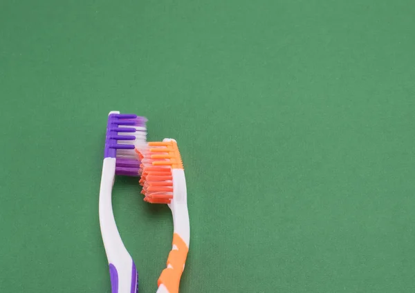 Toothbrushes convey the human relationship between a man and a woman. Love, hugs, tenderness, affection. Objects depict people's feelings. Green background.