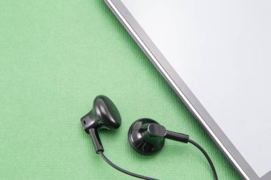 Beyaz kenarlı siyah akıllı telefon (çizgili) daire şeklinde. Gri boş ekran. Ve kulaklıktan kulaklığa yerleştirmek için iki küçük siyah kulaklık. Telefonun yeşil izole bir arkaplanı var.