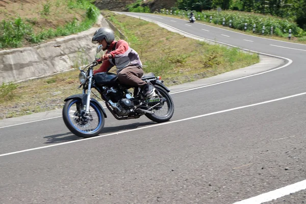 Uomo in sella ad una moto classica sull'autostrada di montagna — Foto Stock