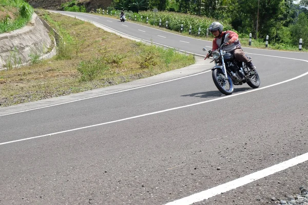 Uomo in sella ad una moto classica sull'autostrada di montagna — Foto Stock