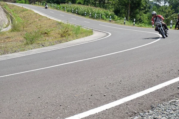 Чоловік їде на класичному мотоциклі на шосе гори — стокове фото