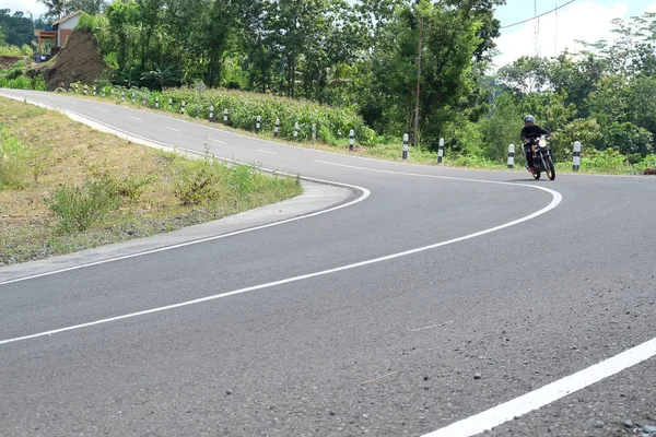 Uomo in sella ad una moto classica sull'autostrada di montagna — Foto Stock