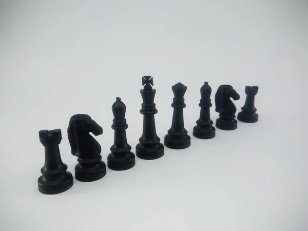 Noir en plastique roi reine évêque chevalier tour aligner pièce d'échecs isolé sur un fond blanc — Photo