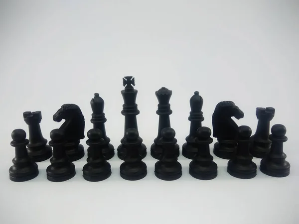 Black plastic king queen bishop knight rook pawn line up chess piece isolated on a white background — ストック写真