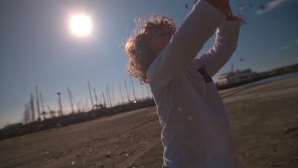 Jovem menino jogando confete na praia — Vídeo de Stock