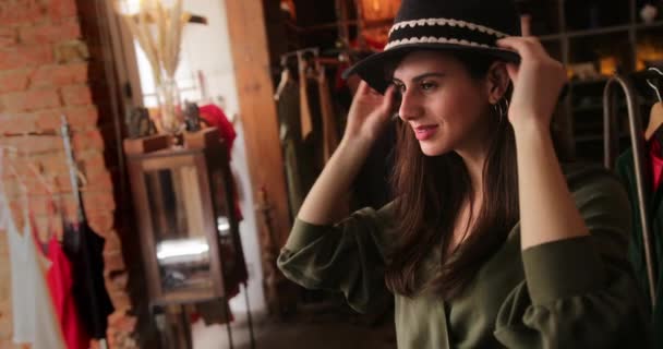 Mujer joven feliz probando sombrero en tienda vintage — Vídeos de Stock