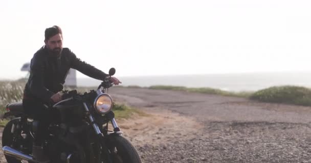 ハンサムなバイカーの男に乗って古典的なバイクで海辺 — ストック動画