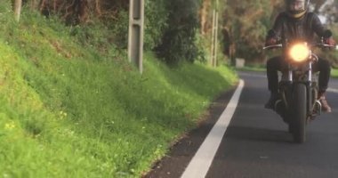 Motosikletli adam Country Road 'da klasik motosiklet sürüyor.
