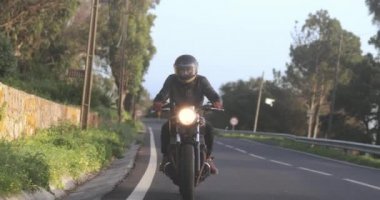 Motosikletli adam Country Road 'da klasik motosiklet sürüyor.