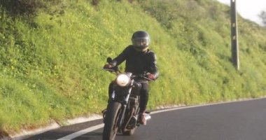 Motosikletli adam Country Road 'da klasik motosiklet sürüyor.