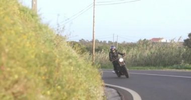 Motosikletli adam Country Road 'da klasik motosiklet sürüyor.