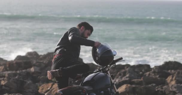 Hombre guapo con chaqueta de cuero bajando de la motocicleta clásica — Vídeos de Stock