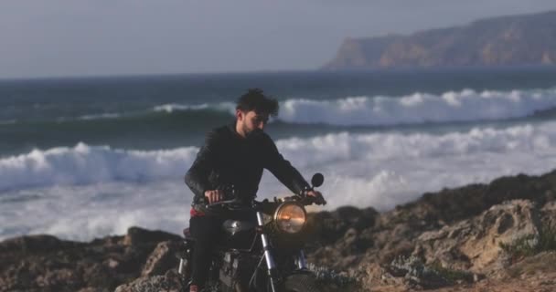 Guapo motociclista cabalgando en motocicleta por el paseo marítimo — Vídeo de stock