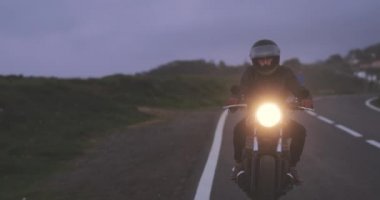 Motosikletli adam Country Road 'da klasik motosiklet sürüyor.