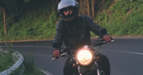 Biker fährt klassisches Motorrad auf Landstraße bei Sonnenuntergang — Stockvideo