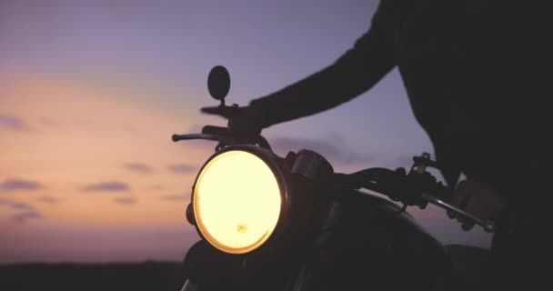 Acercamiento hombre a caballo fuera durante la puesta del sol en la motocicleta clásica — Vídeo de stock