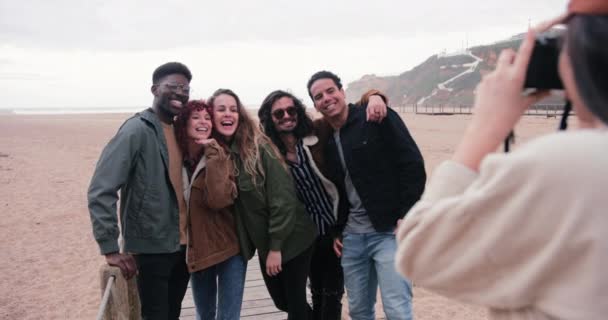 Vrouw neemt foto van een groep vrienden op het strand — Stockvideo