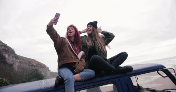 Женщины сидят на крыше фургона и делают селфи со смартфоном — стоковое видео