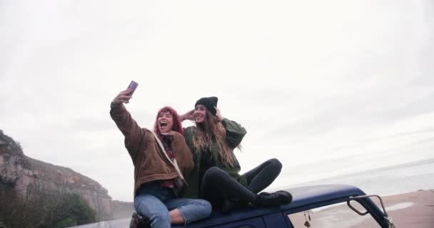 Women sitting on top of van taking selfie with smartphone — Stock Video